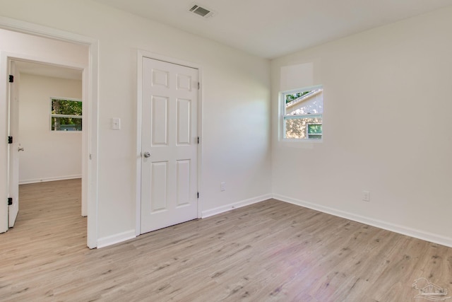 empty room with a wealth of natural light and light hardwood / wood-style flooring