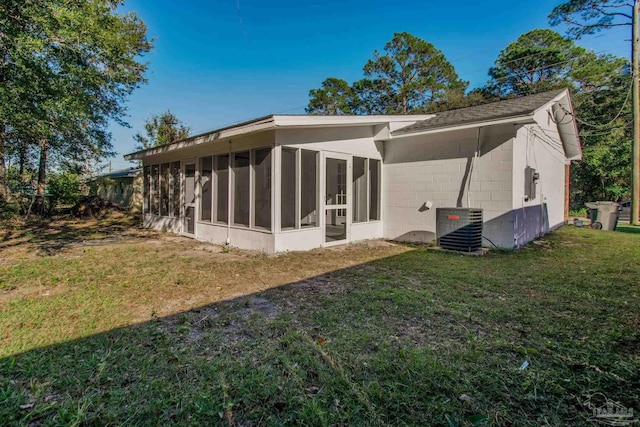 back of house with central AC unit, a sunroom, and a yard