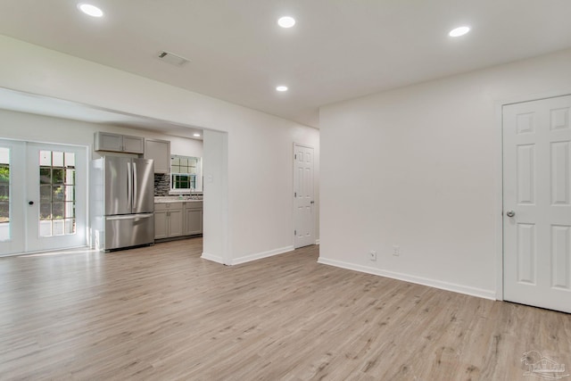 unfurnished living room featuring french doors and light wood-type flooring