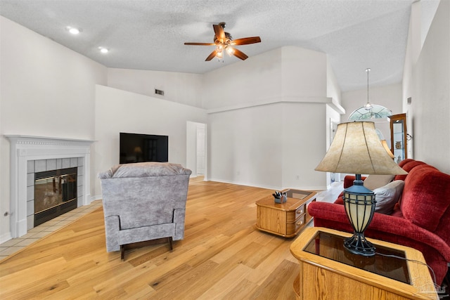 living room featuring a textured ceiling, a fireplace, hardwood / wood-style flooring, and ceiling fan