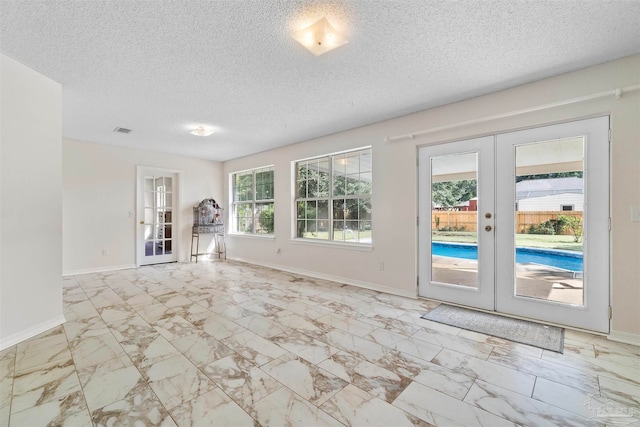 interior space featuring french doors, a healthy amount of sunlight, and a textured ceiling