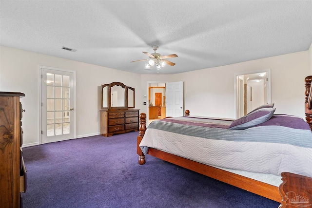 bedroom featuring ceiling fan, a textured ceiling, ensuite bathroom, and dark carpet