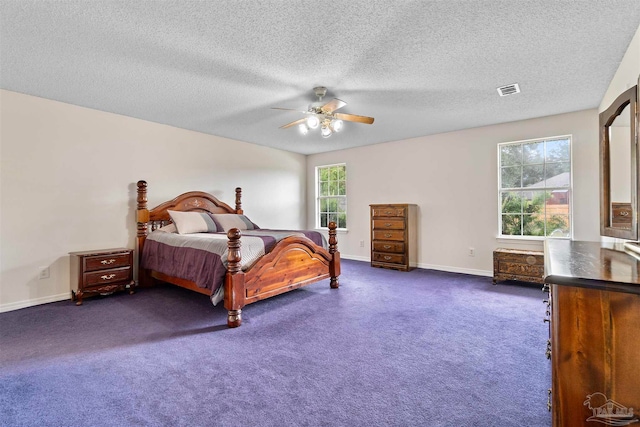 bedroom featuring a textured ceiling, dark colored carpet, multiple windows, and ceiling fan