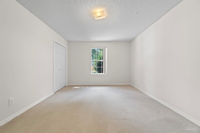 carpeted empty room featuring a textured ceiling