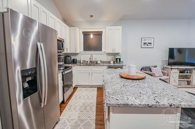 kitchen with stainless steel appliances, light stone countertops, white cabinets, decorative light fixtures, and sink