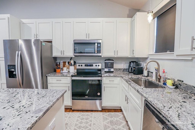 kitchen with stainless steel appliances, white cabinetry, hanging light fixtures, and sink