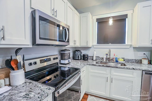 kitchen featuring stainless steel appliances, white cabinets, sink, and hanging light fixtures