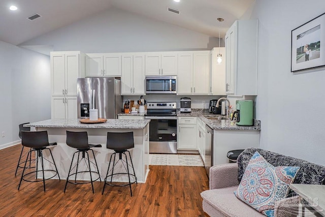 kitchen with white cabinets, stainless steel appliances, light stone counters, and sink