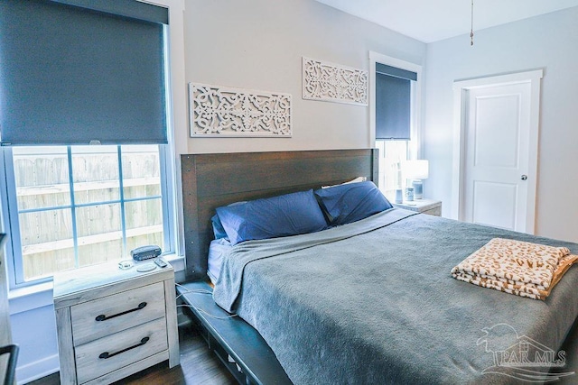 bedroom with multiple windows and dark hardwood / wood-style floors