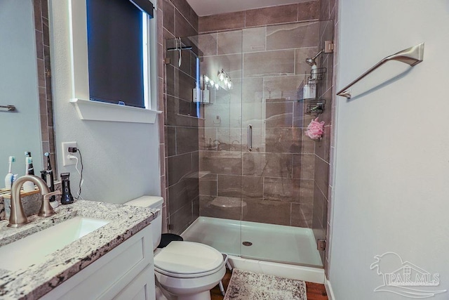 bathroom featuring toilet, vanity, a shower with shower door, and hardwood / wood-style floors