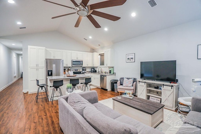 living room featuring ceiling fan, lofted ceiling, sink, and wood-type flooring