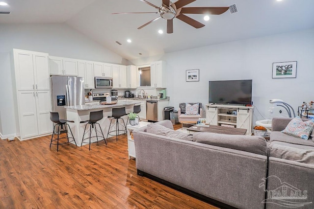 living room with vaulted ceiling, ceiling fan, wood-type flooring, and sink