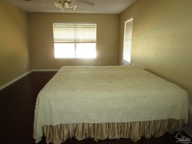 bedroom featuring baseboards, ceiling fan, and dark wood finished floors