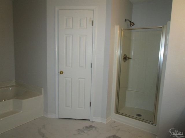 full bath with a stall shower, a garden tub, marble finish floor, and baseboards
