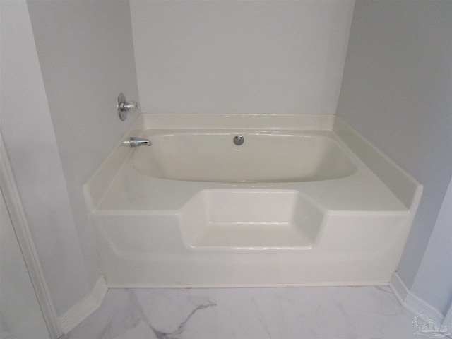 full bath with a tub, marble finish floor, and baseboards