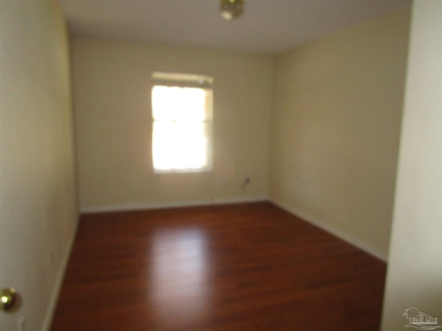 spare room featuring baseboards and wood finished floors