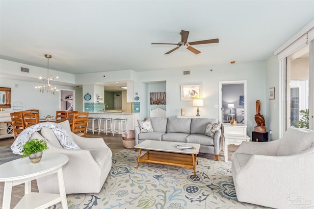 living room featuring light wood-type flooring and ceiling fan with notable chandelier