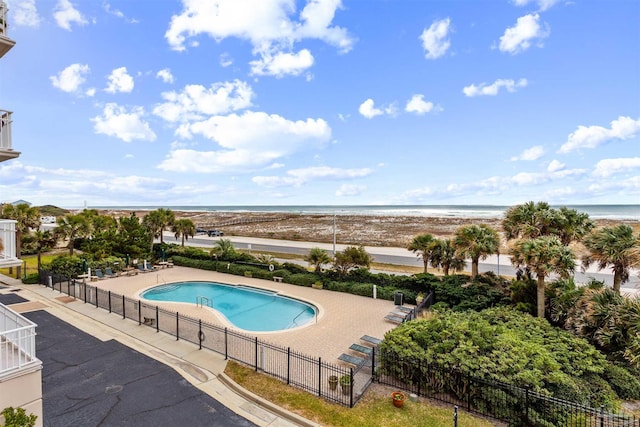 view of pool featuring a view of the beach, a water view, and a patio