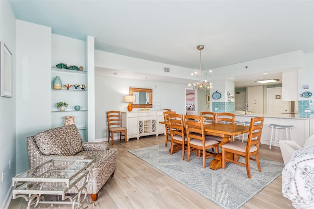 dining room with an inviting chandelier, light hardwood / wood-style flooring, and sink