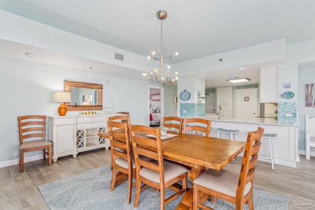 dining area with light hardwood / wood-style floors, sink, and a chandelier