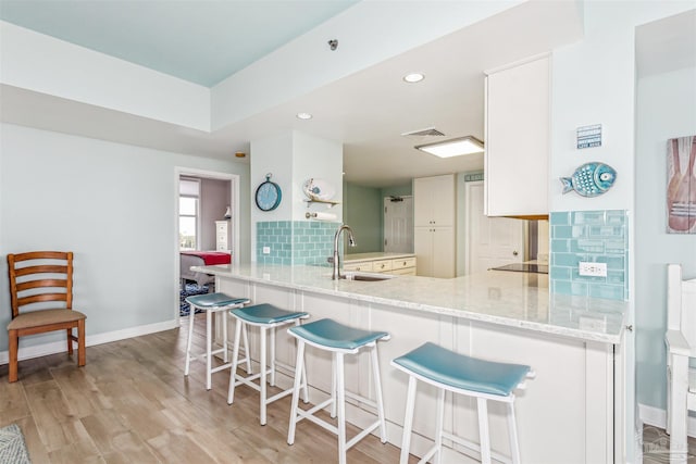 kitchen with light stone counters, sink, kitchen peninsula, and tasteful backsplash