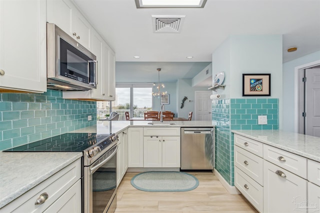 kitchen featuring white cabinetry, stainless steel appliances, a notable chandelier, pendant lighting, and sink