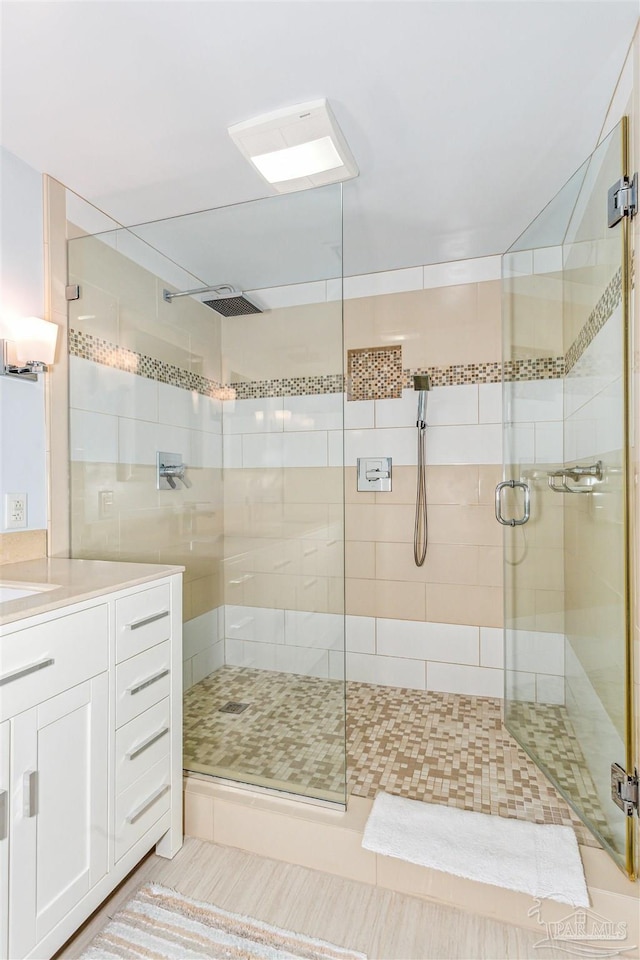 bathroom featuring a shower with door and vanity