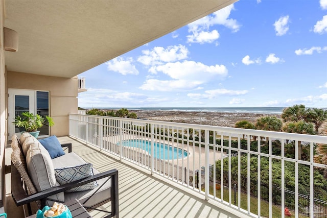 balcony featuring a patio, a water view, and a view of the beach