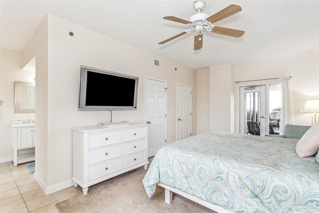 bedroom with ceiling fan, ensuite bathroom, access to exterior, light tile patterned flooring, and multiple closets