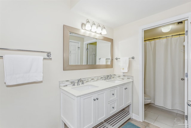 bathroom with tile patterned flooring, toilet, vanity, and tasteful backsplash