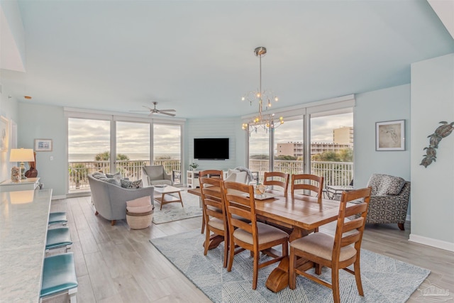 dining space with ceiling fan with notable chandelier and light hardwood / wood-style floors