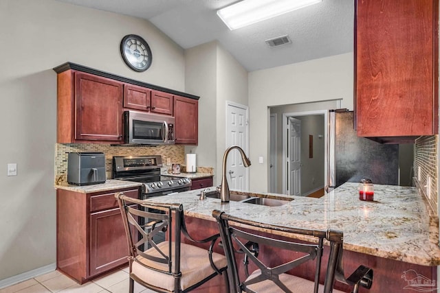 kitchen featuring sink, light stone countertops, tasteful backsplash, light tile patterned flooring, and stainless steel appliances