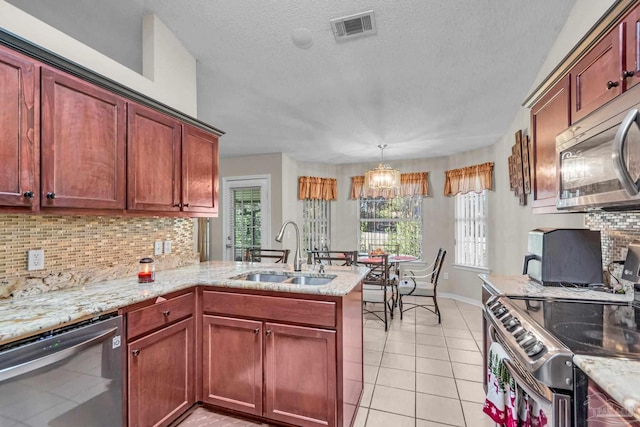 kitchen with backsplash, sink, appliances with stainless steel finishes, decorative light fixtures, and kitchen peninsula