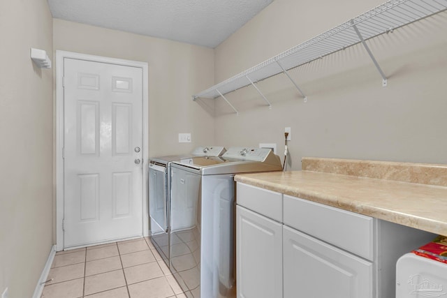 clothes washing area featuring light tile patterned floors, washer and dryer, and a textured ceiling