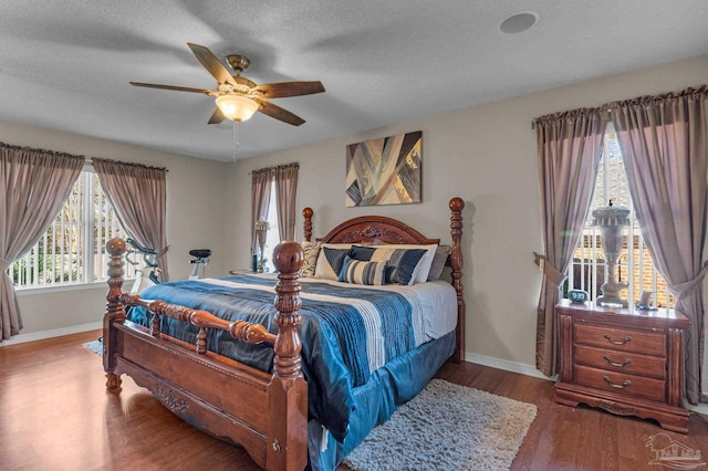 bedroom featuring ceiling fan, wood-type flooring, a textured ceiling, and multiple windows