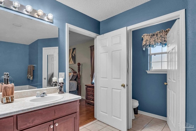 bathroom with tile patterned floors, vanity, a textured ceiling, and toilet