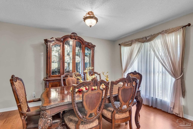 dining room with light hardwood / wood-style flooring and a textured ceiling