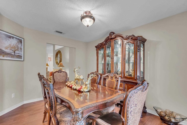 dining space featuring hardwood / wood-style floors and a textured ceiling