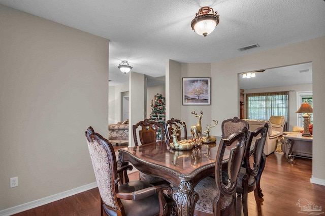 dining room featuring a textured ceiling and dark hardwood / wood-style floors