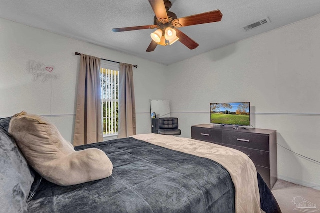 carpeted bedroom with ceiling fan and a textured ceiling