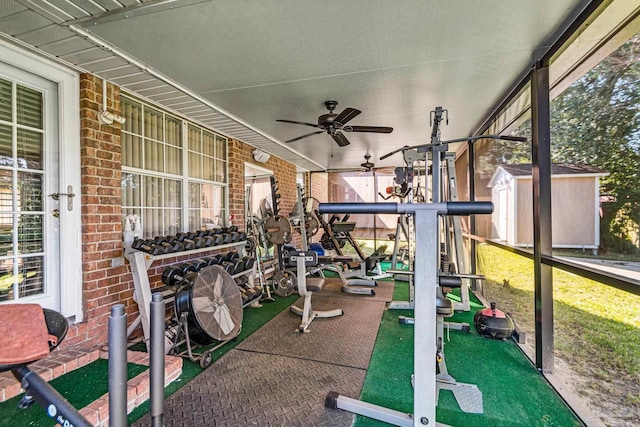 exercise room featuring ceiling fan and brick wall