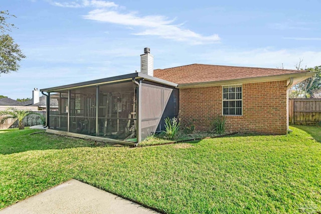 rear view of house featuring a sunroom and a yard