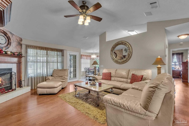 living room with a fireplace, hardwood / wood-style floors, ceiling fan, and lofted ceiling