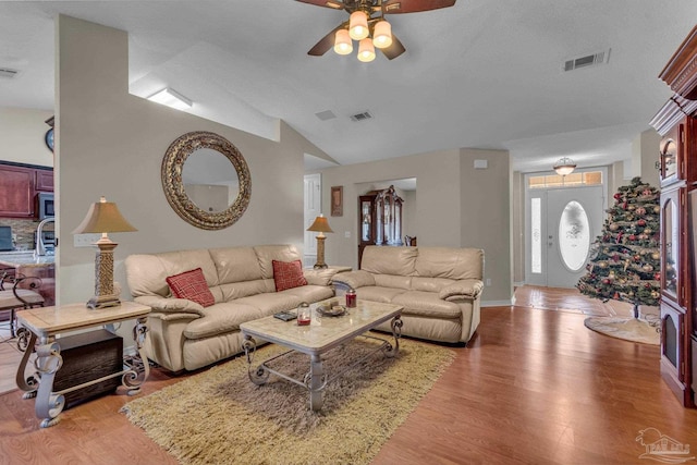 living room with hardwood / wood-style floors, ceiling fan, and lofted ceiling