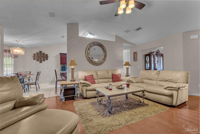 living room featuring ceiling fan with notable chandelier, light hardwood / wood-style flooring, and lofted ceiling