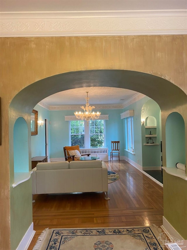 interior space with an inviting chandelier, wood-type flooring, and crown molding