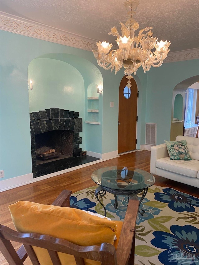 living room with a notable chandelier, a textured ceiling, hardwood / wood-style flooring, and ornamental molding