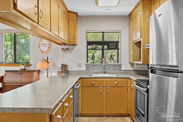 1948 Tanbark Dr, Milton, FL 32583 - kitchen featuring appliances with stainless steel finishes, a sink, a peninsula, a textured ceiling, and brown cabinets