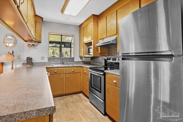 1948 Tanbark Dr, Milton, FL 32583 - kitchen featuring appliances with stainless steel finishes, a sink, under cabinet range hood, light wood-style floors, and backsplash