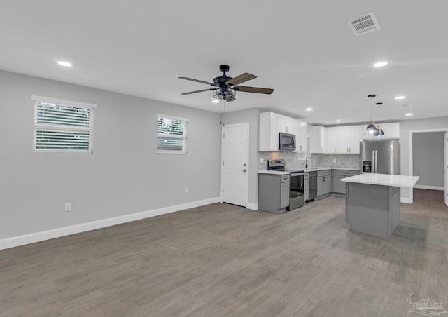 kitchen featuring pendant lighting, light wood-type flooring, appliances with stainless steel finishes, and a healthy amount of sunlight